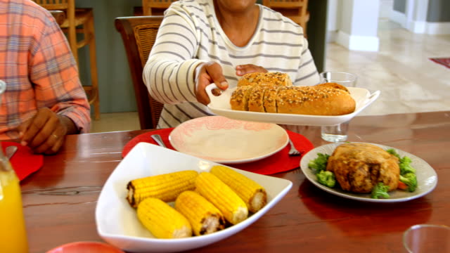 Vista-de-fuente-de-la-familia-black-tener-comida-en-la-mesa-de-comedor-en-una-casa-confortable-4k