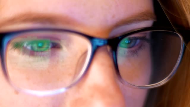 Nahaufnahme-Reflexion-des-Laptop-Bildschirm-in-den-Gläschen-der-caucaisna-Mädchen-Hacker,-Blick-auf-Copmuter,-schöne-Augen-von-klugen-Menschen-innen