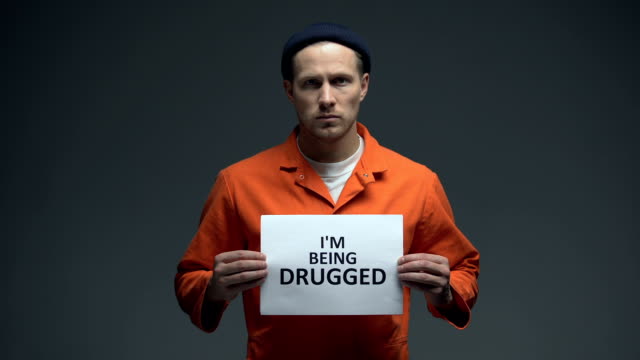 Hombre-encarcelado-europeo-sosteniendo-que-estoy-siendo-drogado-señal-en-la-célula,-ADVERTENCIA,-adicto