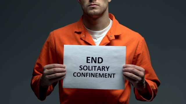 End-solitary-confinement-phrase-on-card-in-hands-of-Caucasian-prisoner,-protest