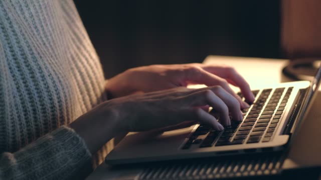 Hands-of-woman-working-on-laptop-in-dark-room.-Close-up