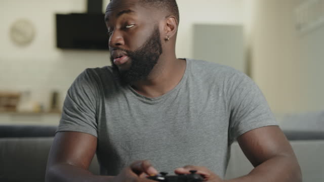 Hombre-negro-jugando-videojuegos-en-casa.-Un-tipo-molesto-sentado-con-una-estación-de-juegos.