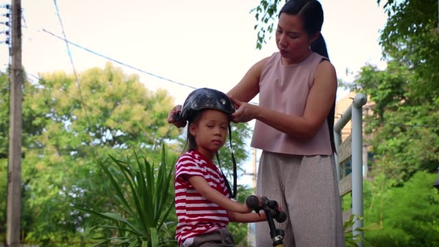 Mutter-hilft-ihrem-Sohn-(Lange-Haare-Junge)-Fahrradhelm-im-Freien-zu-setzen.