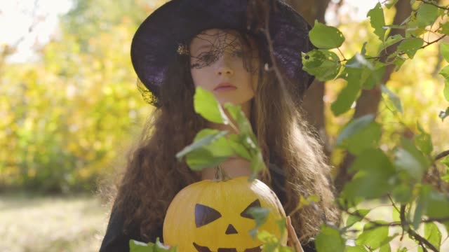 Ernste-Rotschopf-kaukasische-Mädchen-in-Halloween-Hexe-Kostüm-stehend-im-Herbstpark-gekleidet