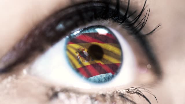 Frau-blaues-Auge-in-Nahaufnahme-mit-der-Flagge-von-Spain-in-Iris-mit-Windbewegung.-Videokonzept