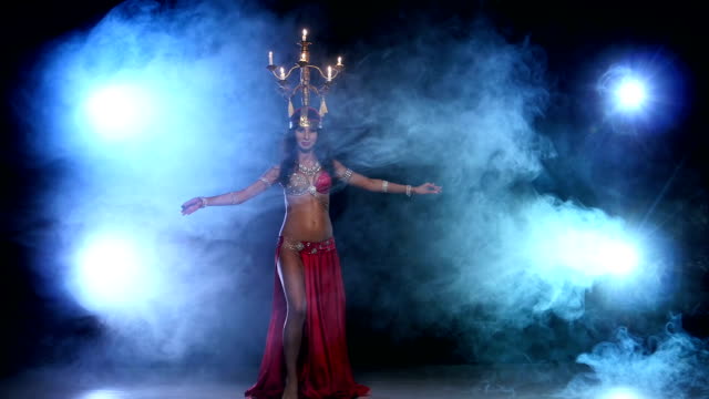 Attractive-belly-dancer-starts-dancing-with-candles-on-her-head,-black,-smoke