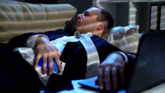 Tired-businessman-is-sleeping-on-the-sofa-at-the-office