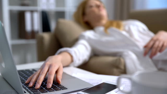 Mujer-de-negocios-cansado-durmiendo-en-el-sofá-en-la-oficina-con-el-ordenador-portátil