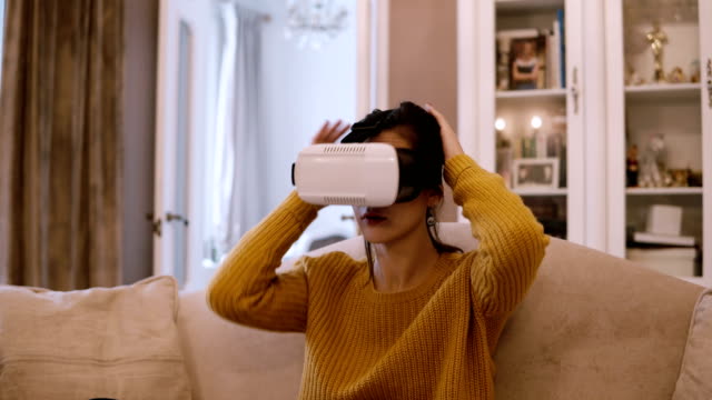 Junge-Frau-trägt-VR-Kopfhörer-zu-Hause,-schaut-sich-um-und-nehmen-Sie-die-Gläser-der-virtuellen-Realität