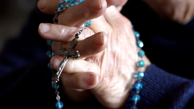 hautnah-auf-Händen-einer-älteren-Frau,-die-mit-den-Rosenkranz-beten