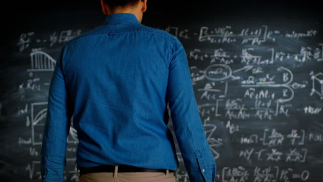Brillante-junge-wissenschaftliche-Ansätze-Blackboard-mit-komplexen-mathematischen-Formel-/-Gleichung-geschrieben-steht,-beginnt-Lösung-nachzudenken.