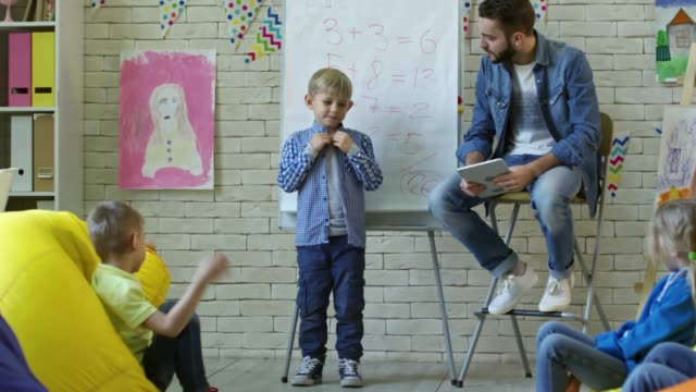 Süsser-Boy-vor-Klassenkameraden-im-Kindergarten-zu-sprechen