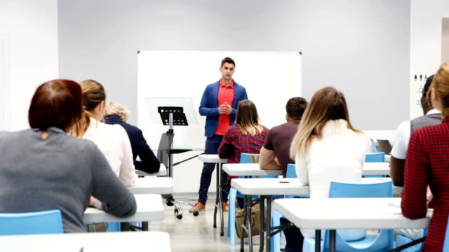 male-student-answering-at-whiteboard-in-front-group-of-students