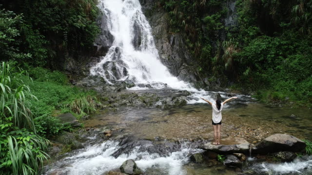 Mujer-de-estilo-de-vida-saludable-haciendo-yoga-cerca-de-cascada-en-el-bosque