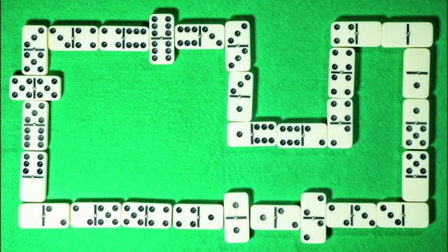 Stop-motion-of-domino-game-on-green-cloth-background.