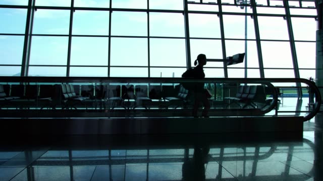Silhouette-of-passengers-walking-in-the-busy-international-terminal-hall-in-the-airport