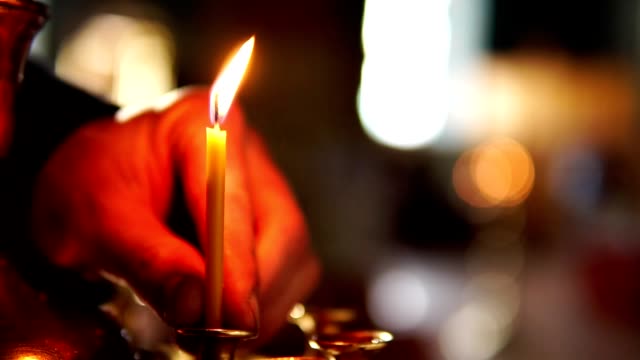 Die-menschliche-Hand-Nahaufnahme-setzt-eine-Kerze-in-eine-Kerze-in-die-christliche-orthodoxe-Kirche