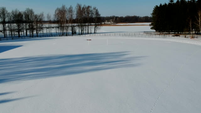 Drone-vuela-sobre-el-campo-de-fútbol-de-estadio-cubierto-de-nieve-de-invierno