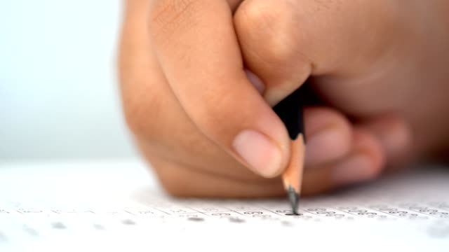 Examination-test-concept,-close-up-pencil-on-test-answer-paper,-pencil-on-hand-of-student-in-examination-classroom.-It-multiple-choice-for-assessment-of-knowledge-evaluation-graduate-education