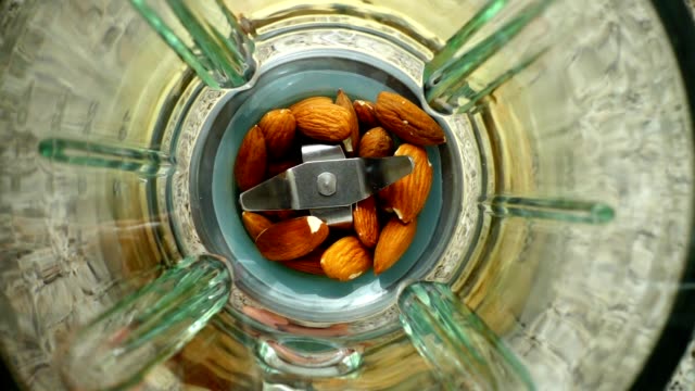 Crushing-of-almonds-in-the-blender.-Slow-motion.	Knives-crush-almonds.-Top-view.