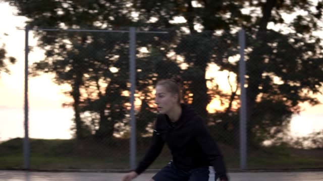 Handhelded-footage-of-a-young-girl-basketball-player-training-and-exercising-outdoors-on-the-local-court.-Dribbling-with-the-ball,-bouncing-and-make-a-shot