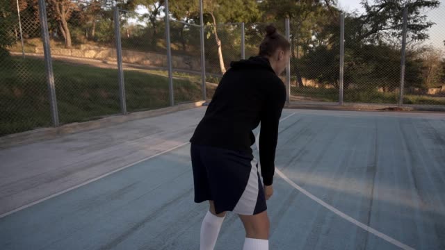 Seltener-Blick-auf-eine-lange-Distanz-werfen-von-jungen-weiblichen-Basketball-Spieler-üben-auf-dem-im-freien-lokalen-Basketball-Platz.-Bäume-und-Sonne-scheint-vor-dem-Hintergrund