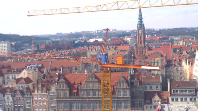 Vista-aérea-en-grúas-de-construcción-y-panorama-del-casco-antiguo-de-Gdansk-en-4-k-lenta-60fps
