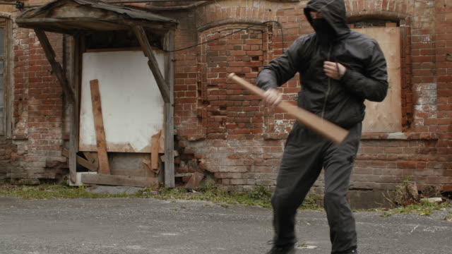 Aggressive-Bandit-in-schwarzer-Maske-und-Haube-training-mit-Baseballschläger-zu-kämpfen
