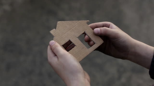 Obdachloser-junge-hält-ein-Karton-Haus