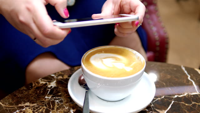 Mujer-tomando-una-imagen-de-la-taza-de-latte-arte-café-sobre-la-mesa-en-4k-lento-movimiento-60fps