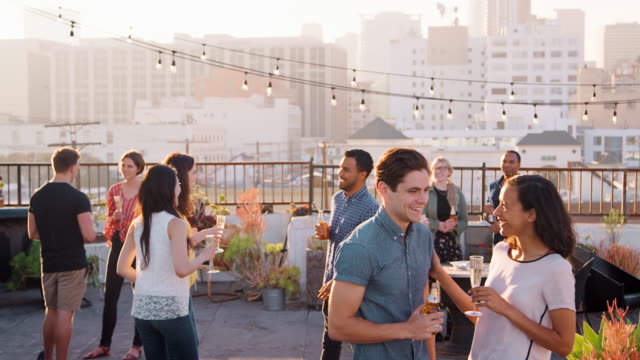 Freunde-versammelt-auf-Dachterrasse-für-Party-mit-Skyline-der-Stadt-im-Hintergrund