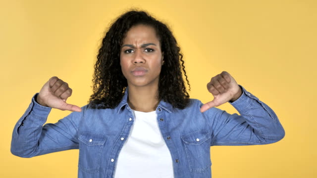 African-Girl-Gesturing-Thumbs-Down-Isolated-on-Yellow-Background