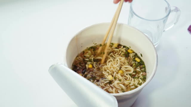 Someone-mixes-instant-noodles-and-hot-water-with-chopsticks-in-a-paper-bowl.