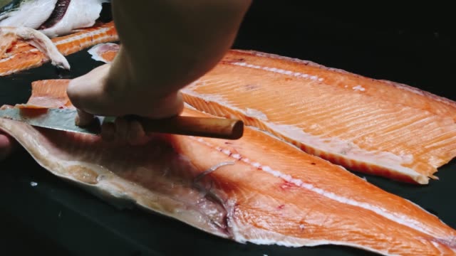 Chef-takes-out-bones-from-the-salmon-fillet,-cutting-fish-on-slices-for-cooking-sushi-in-4k-resolution-in-slow-motion