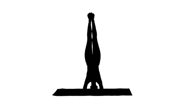 Silhouette-schöne-junge-Frau-tut-Yoga-Übung-Variation-der-unterstützten-Kopfstand,-Garuda-Salamba-Sirsasana-mit-gekreuzten-Beinen