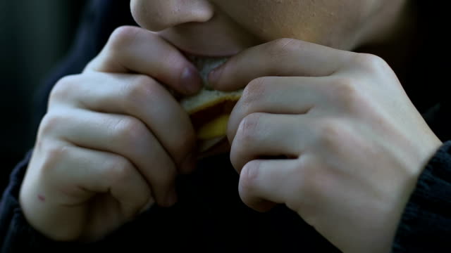 Hungry-homeless-boy-eating-sandwich,-child-living-off-charity,-poverty-closeup