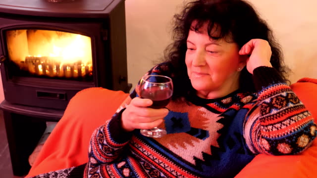 Woman-sitting-by-fireplace-drinking-wine-and-laughing