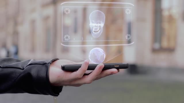 Männliche-Hände-zeigen-auf-Smartphone-konzeptionelle-HUD-Hologramm-menschlicher-Schädel