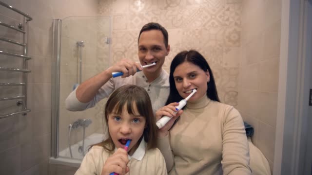 Zahnpflege,-glückliche-Familie-mit-Zahnbürstenbürstenzähnen-vor-dem-Spiegel