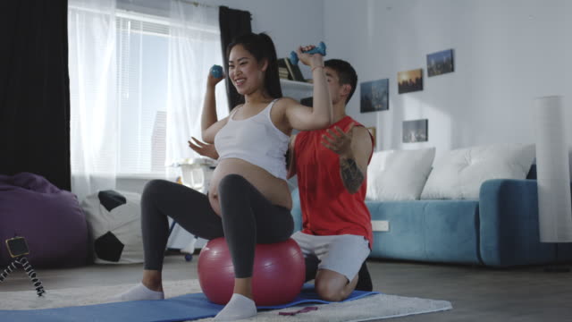 Junger-Mann-weist-schwangere-Frau-während-des-Trainings-an