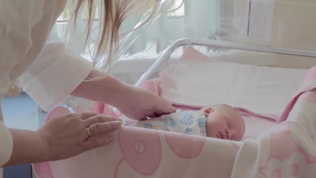Mutter-bedeckt-schlafendes-Neugeborenes-mit-Decke-in-Mutterschaftsklinik