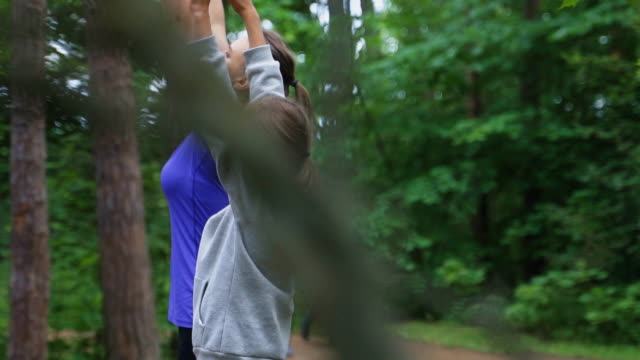 Mutter-und-Tochter-machen-Gymnastik-im-Wald.