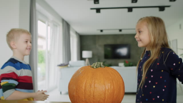 Handheld-view-of-drilled-pumpkin-and-curious-children