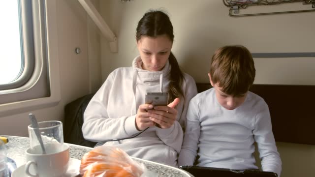 Mom-and-son-in-gadgets-travelling-by-train-is-playing-a-games-in-a-second-class-carriage.