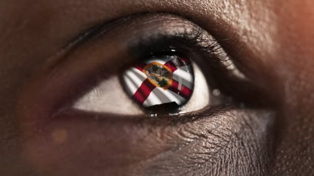 Woman-black-eye-in-close-up-with-the-flag-of-Florida-state-in-iris,-united-states-of-america-with-wind-motion.-video-concept