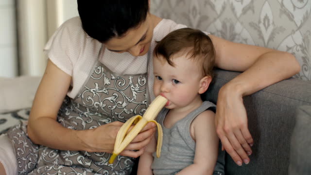 Baby-eats-banana-with-mother's-help