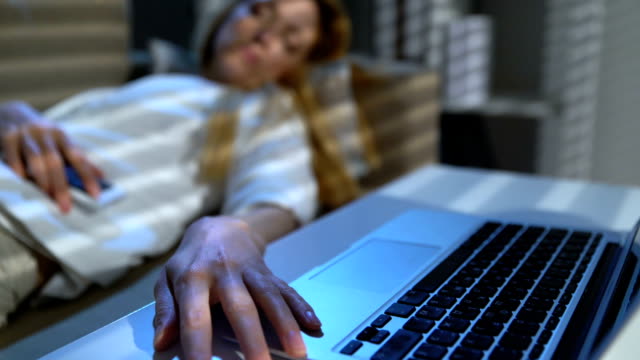 Empresaria-cansada-dormir-en-el-sofá-en-la-oficina-con-ordenador-portátil-y-teléfono