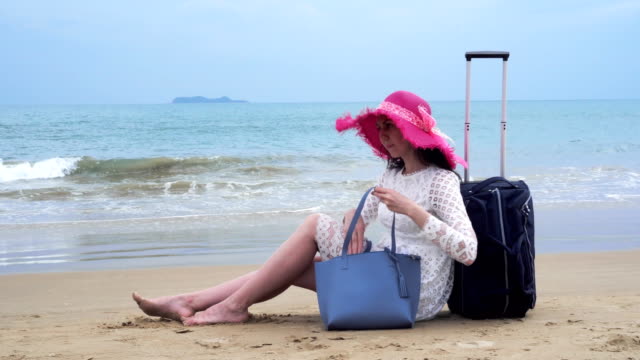 Mädchen-sitzen-am-Strand-mit-ihrer-Bagage-und-Blick