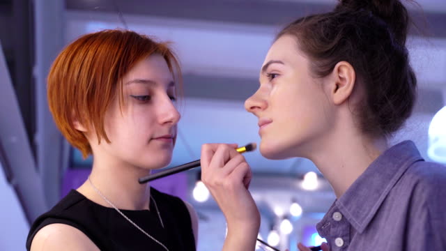 Concepto-de-belleza-y-moda.-Maquilladora-profesional-aplicarse-cosméticos-en-el-rostro-de-la-modelo.-Closeup