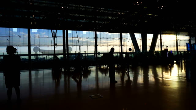 Masse-der-Menschen-Silhouette-zu-Fuß-Kontrast-mit-Morgen-Sonne-Licht-Glasarchitektur-am-Flughafen